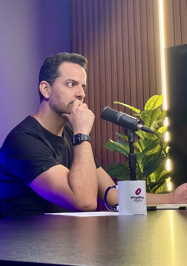 Eric Klein em estúdio, gravando conteúdo com microfone e caderno sobre a mesa.
